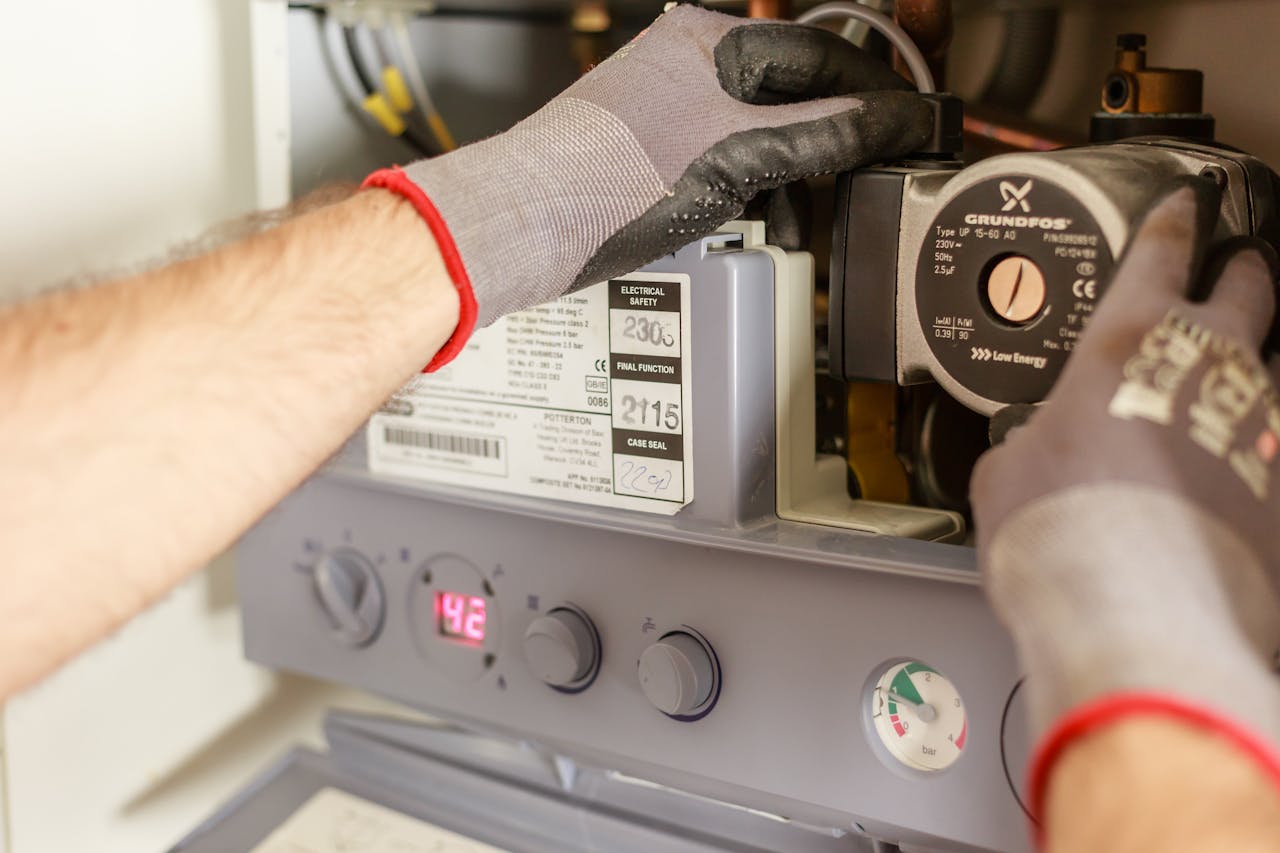 Close-up of hands adjusting a boiler system with precise instrumentation, showing maintenance work.